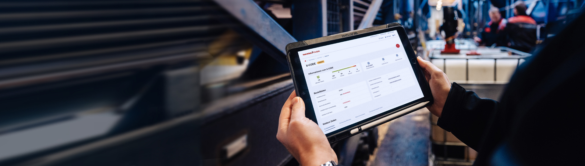 Hände halten Tablet in Produktionshalle von Hansa Flex