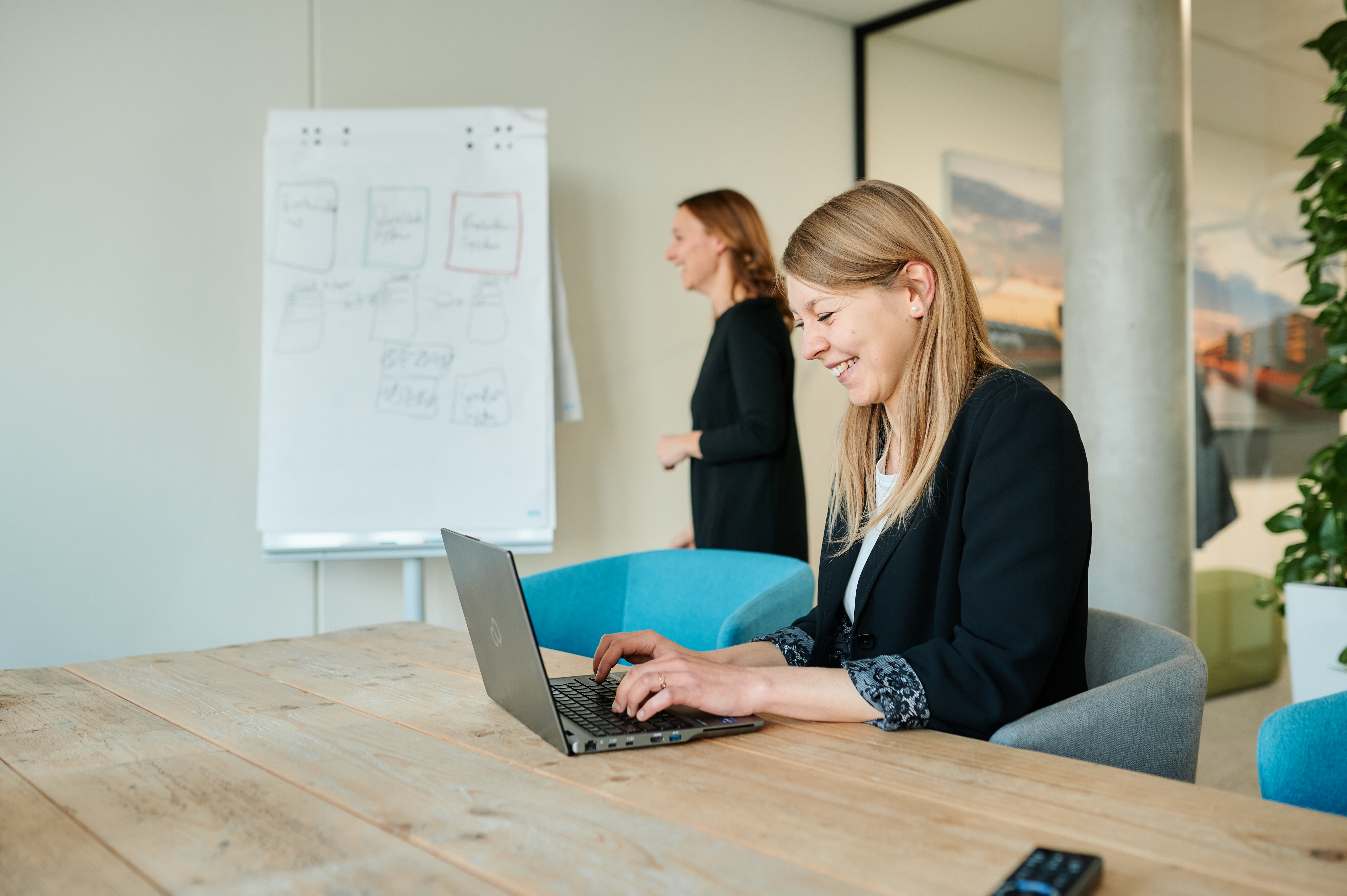 team neusta Mitarbeiterin sitz am Tisch und arbeitet am Laptop