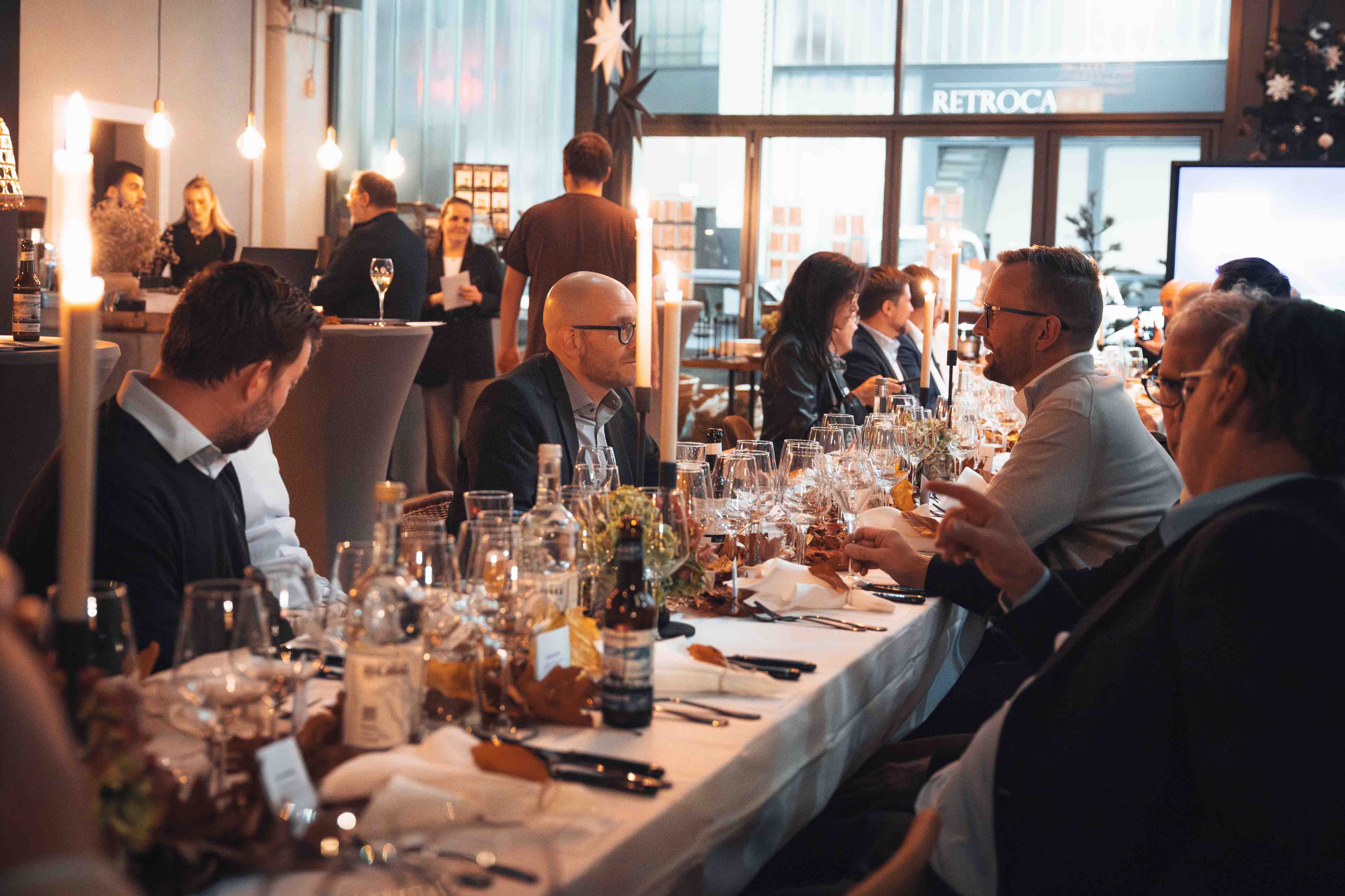 Gruppe Menschen sitzt am gedeckten Tisch beim KI Dinner im Schuppen Eins