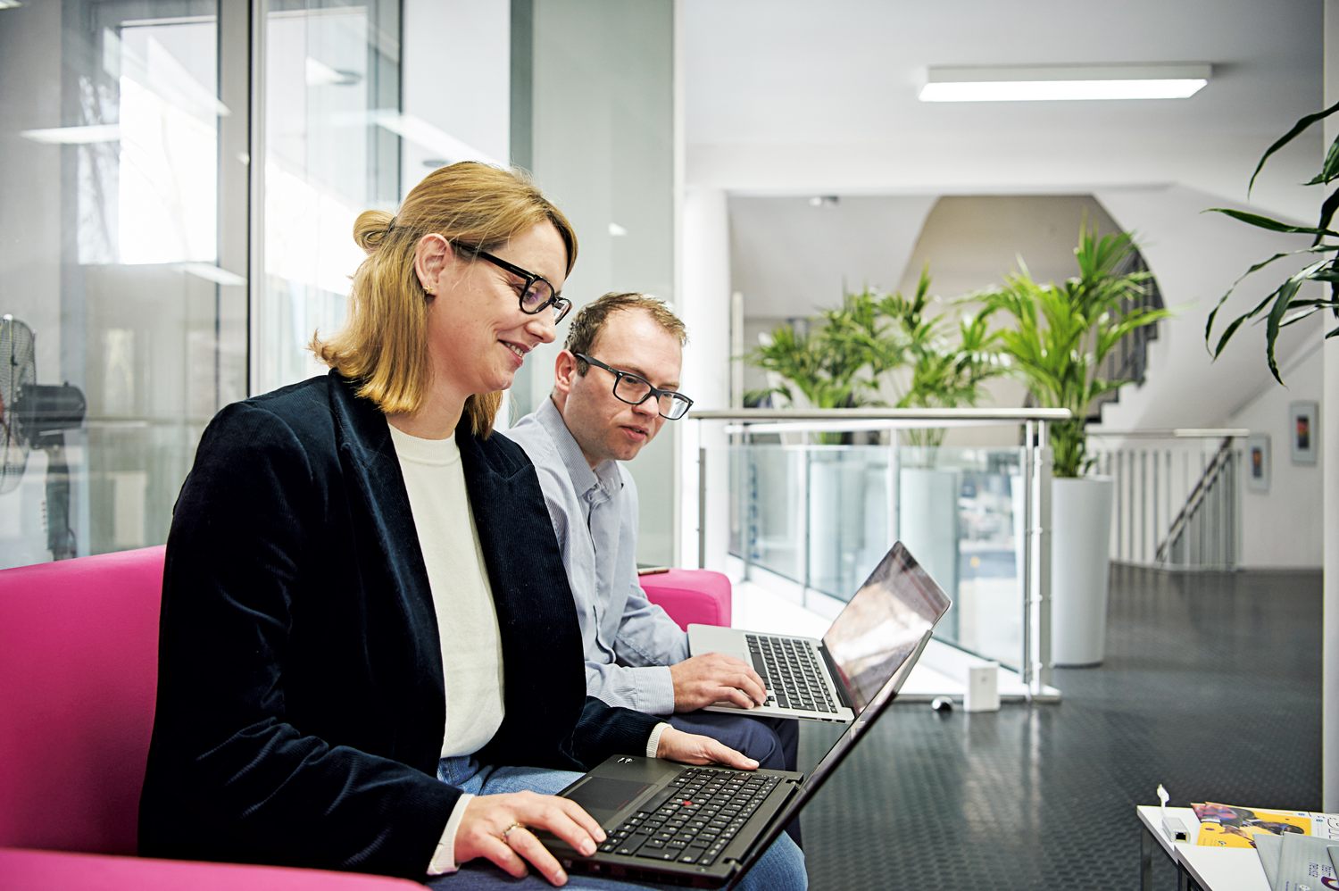 Frau und Mann mit Laptops auf den Knien bei der Weiterbildung