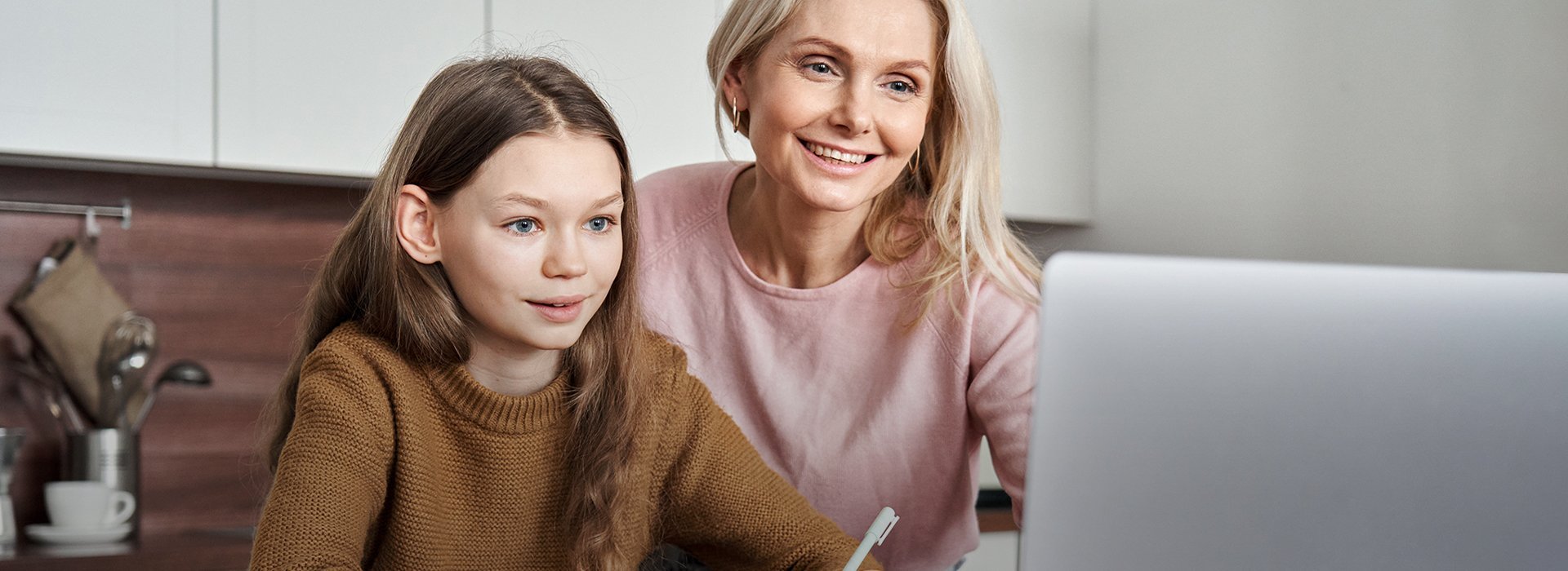 Frau mit Mädchen vor einem Laptop sitzend