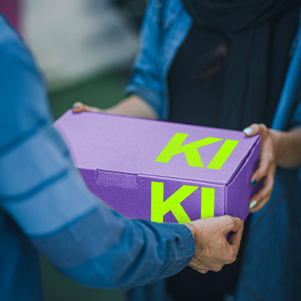 Zwei personen tauschen eine Kiste aus mit dem Schriftzug KI