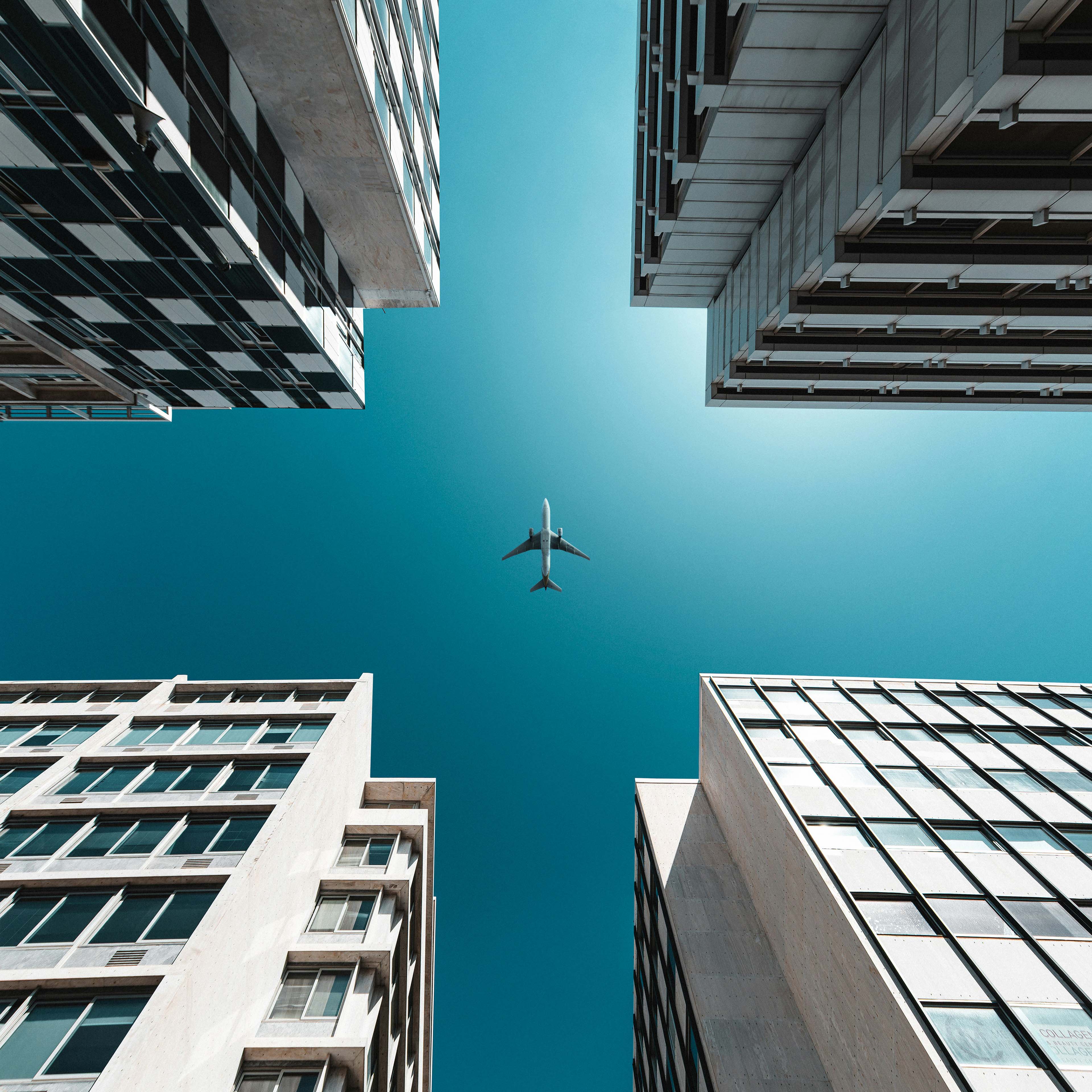 Flugzeug von unten betrachtet am Himmel in der Großstadt zwischen Hochhäusern