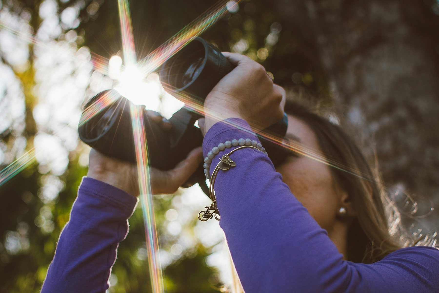 Person hält Fernglas ins Sonnenlicht und blickt in die Ferne.