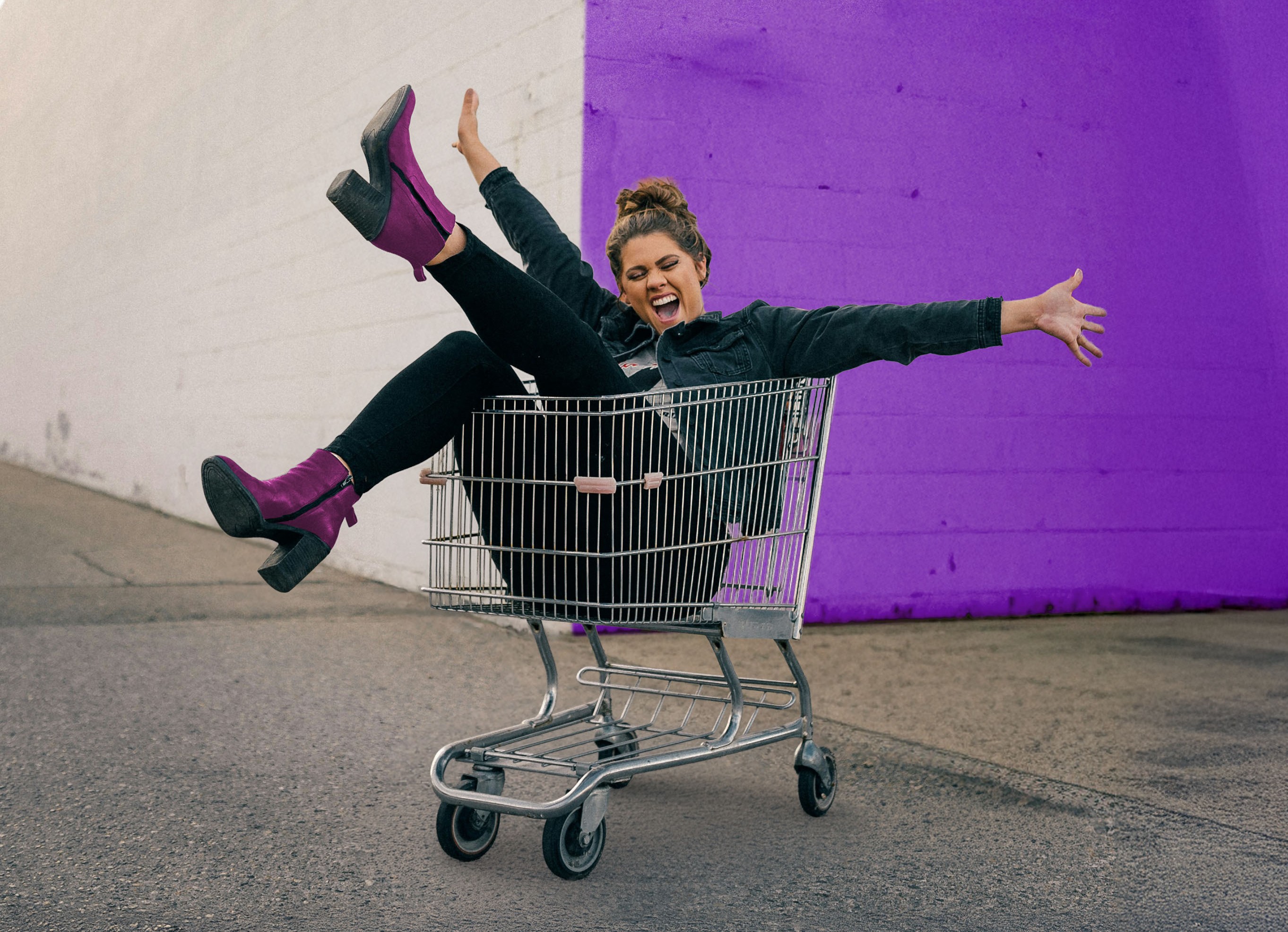 Frau liegt lachend im Einkaufswagen beim Einkaufen