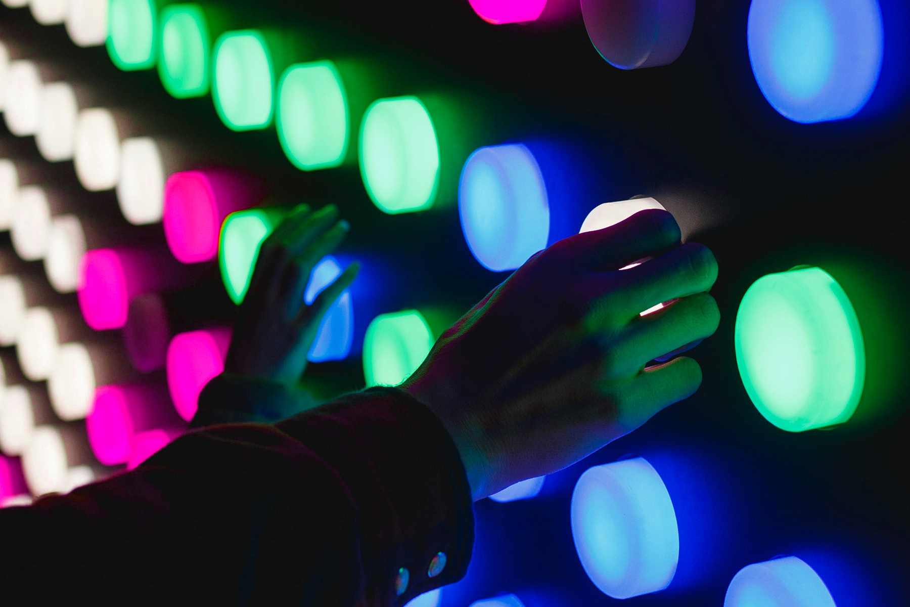 Hand drückt bunte leuchtende Knöpfe im Dunkeln