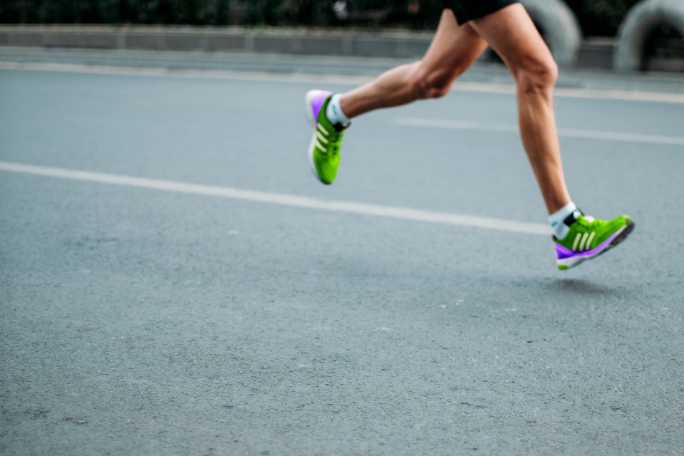 Beine eines Läufers mit Laufschuhen auf der Straße