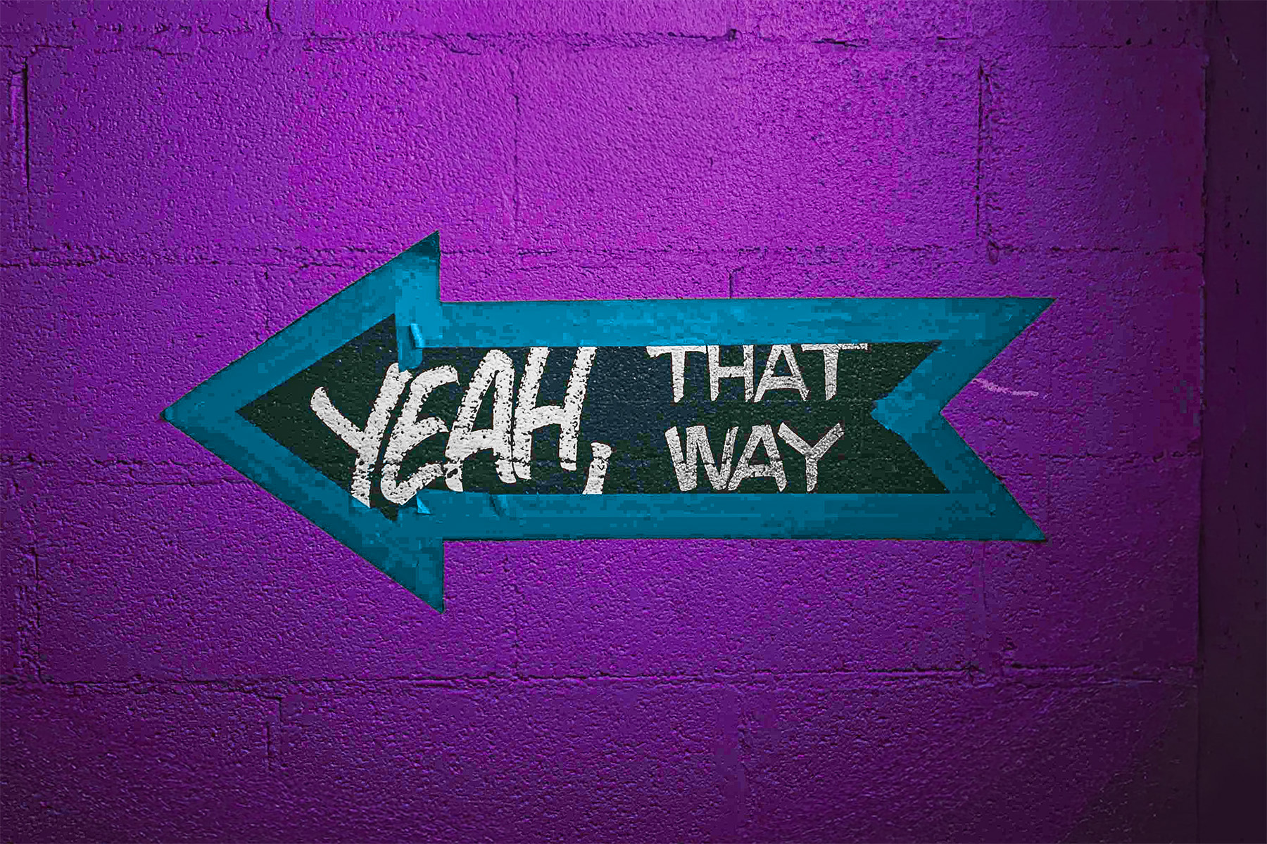 Geklebter Pfeil nach links auf lila Wand mit Schriftzug yeah that way