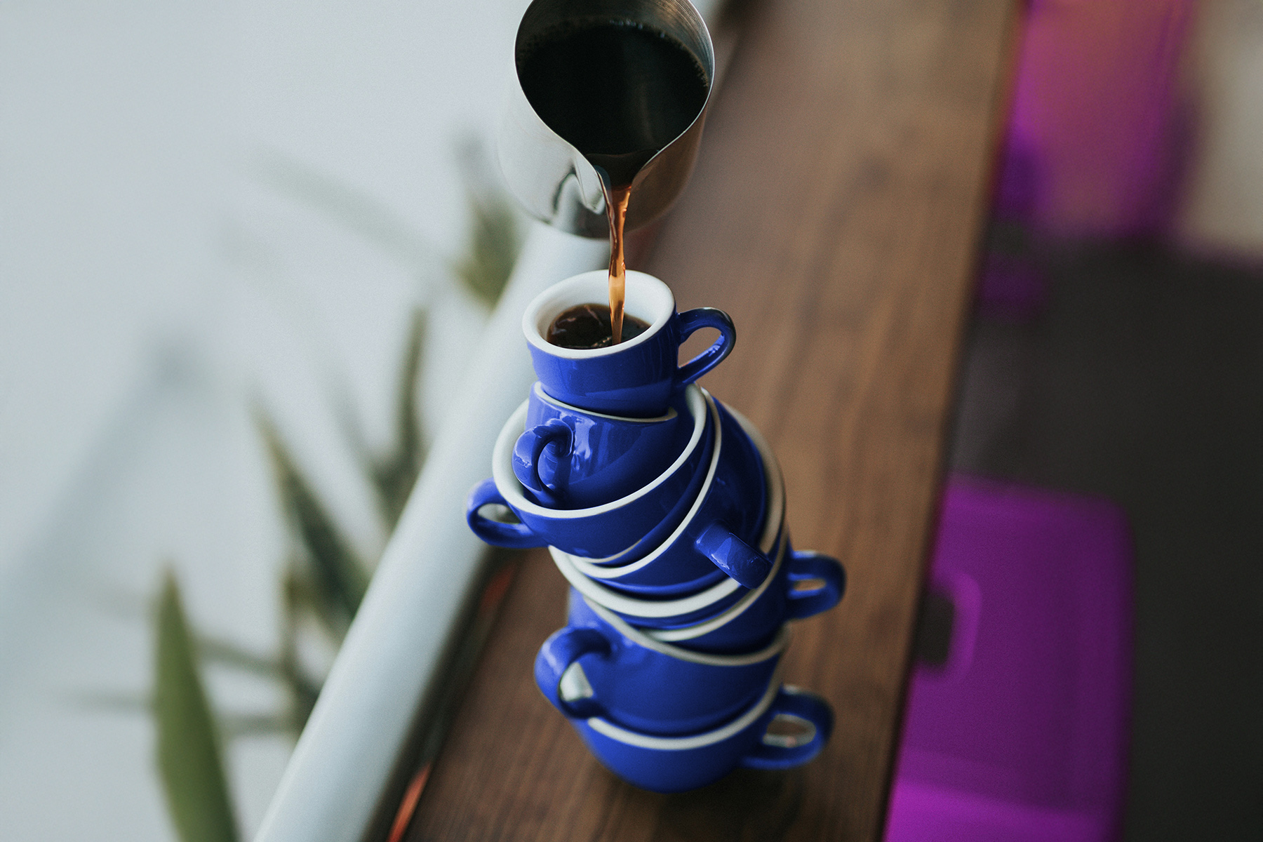 Mehrere blaue Tassen ineinander gestapelt und von oben wird Kaffee eingegossen