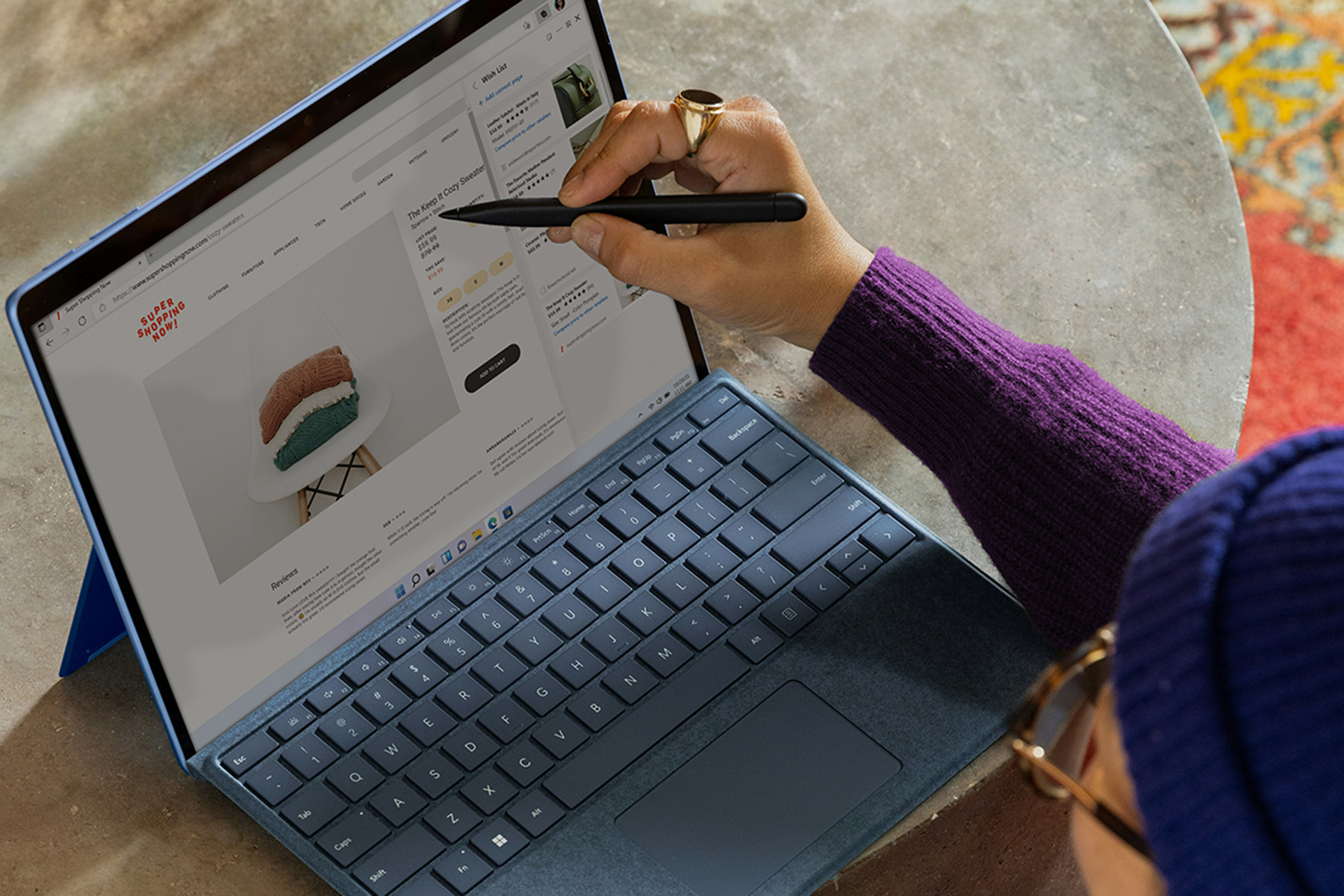 Hand mit Stift in der Hand an einem Tablet mit Tastatur