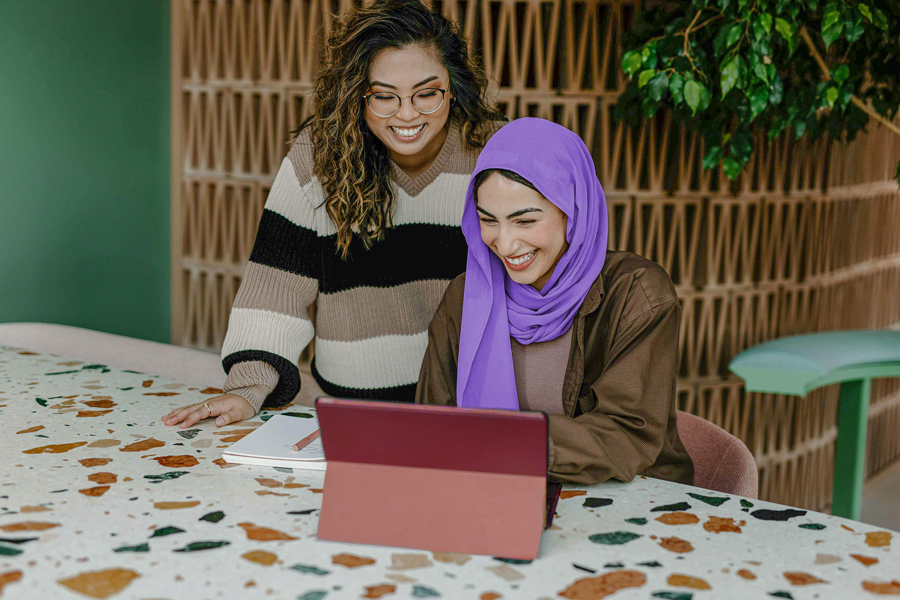 Zwei Frauen eine stehend eine sitzend an einem Tisch vor einem Tablet