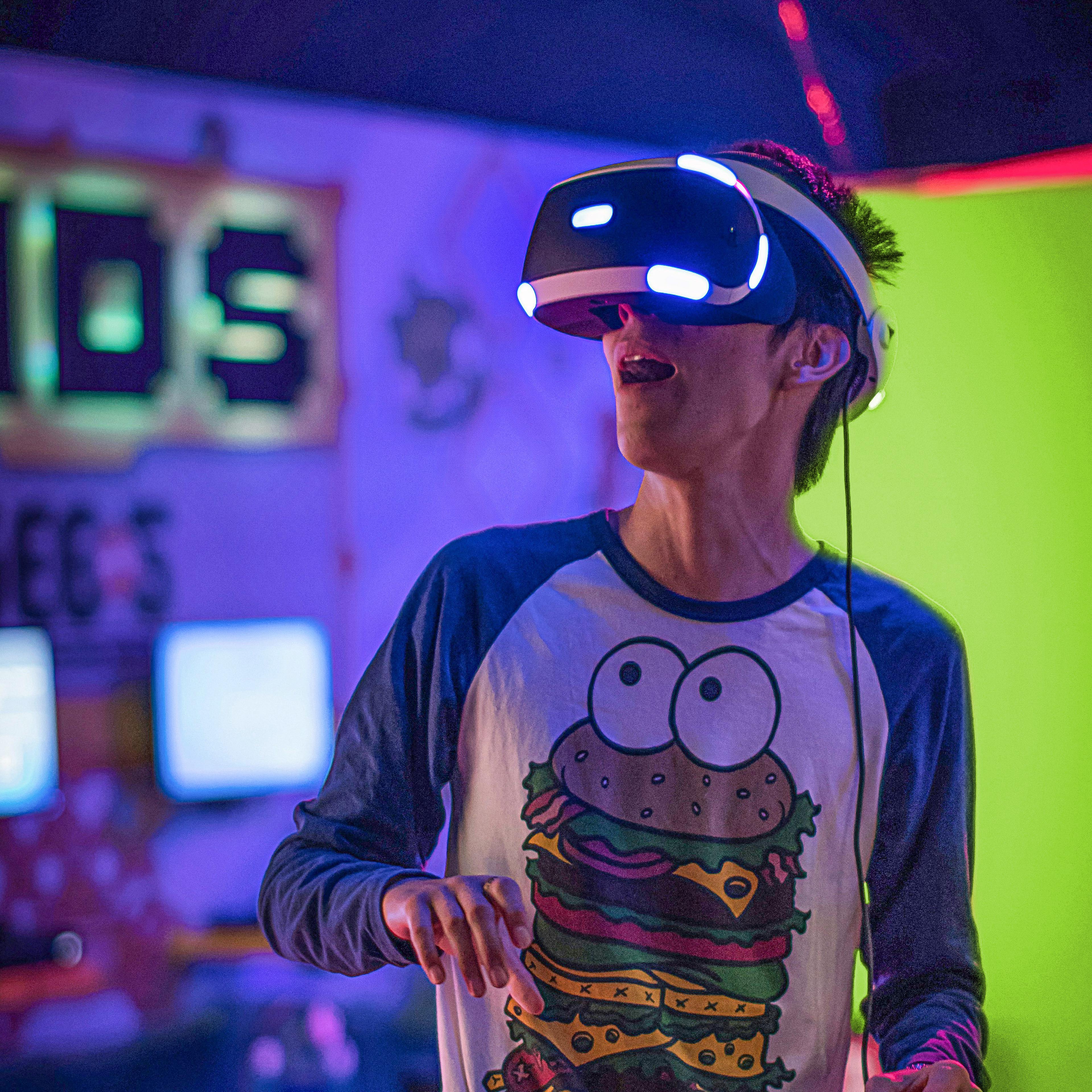 Mann trägt VR Brille und hat ein Langarmshirt mit Burger-Druck an