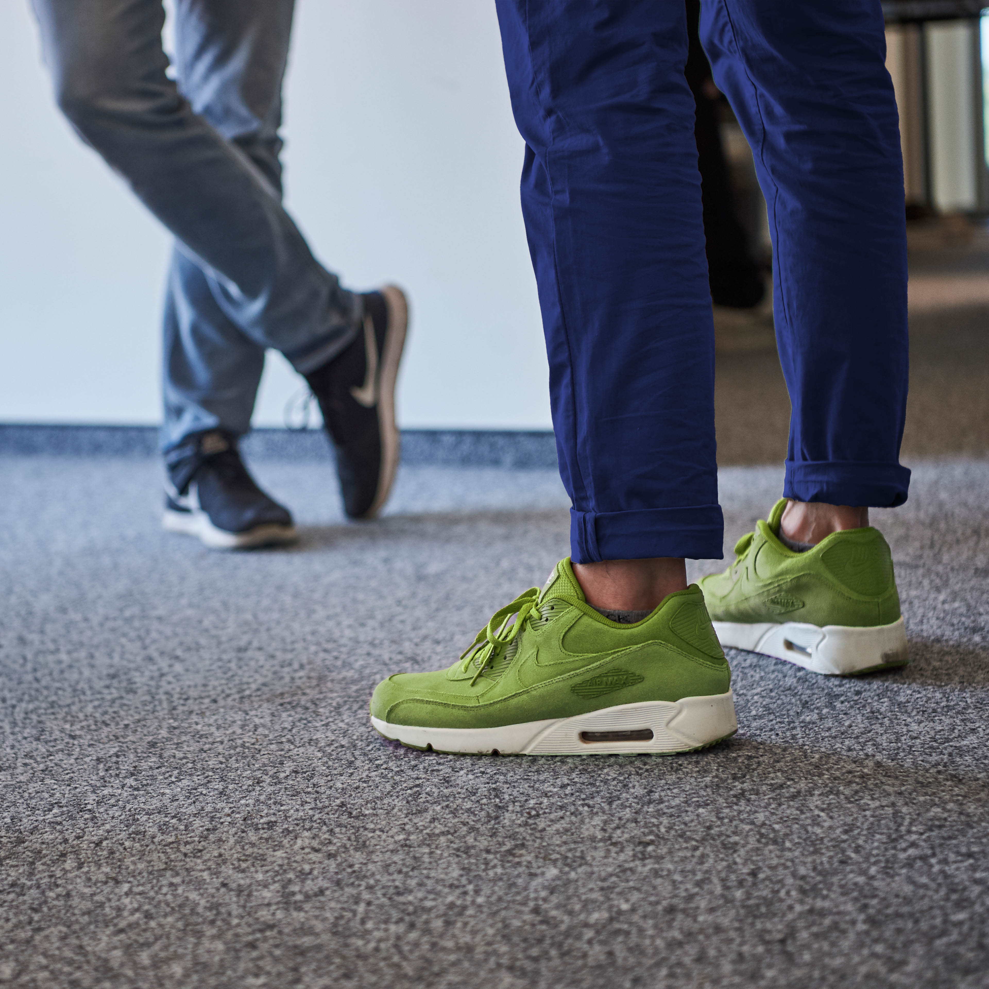 Person mit grünen Sneackern in Büro stehend